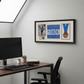 a framed collage of three photos and a medal hanging on a wall above a wooden desk with a computer monitor, keyboard, and mouse.
