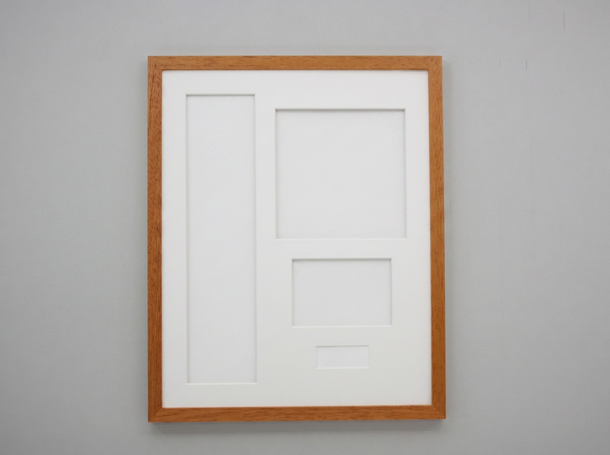 A white picture frame with a brown border is hanging on a gray wall.