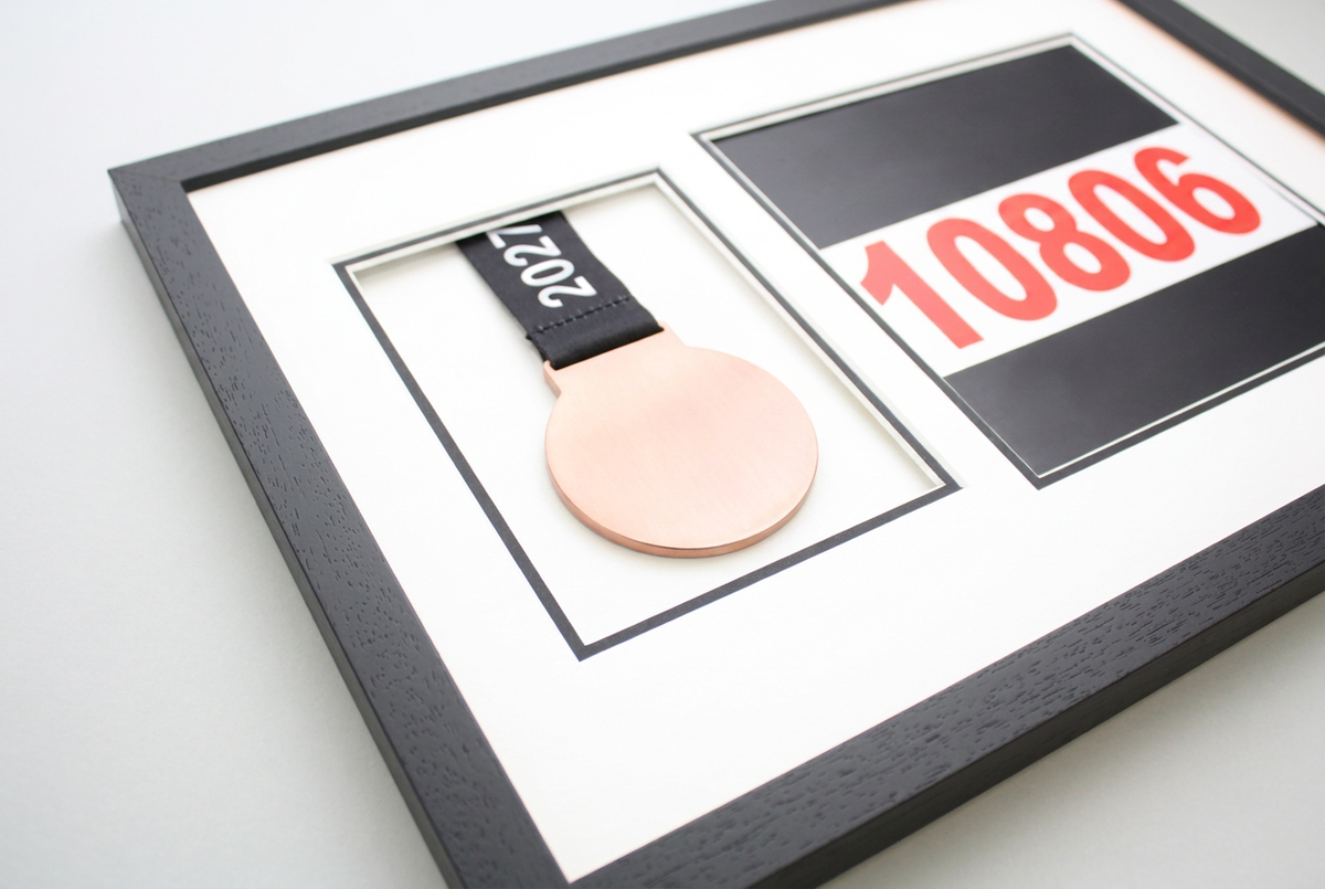 A framed medal with a black ribbon and a number "10806" displayed on the right side of the frame.
