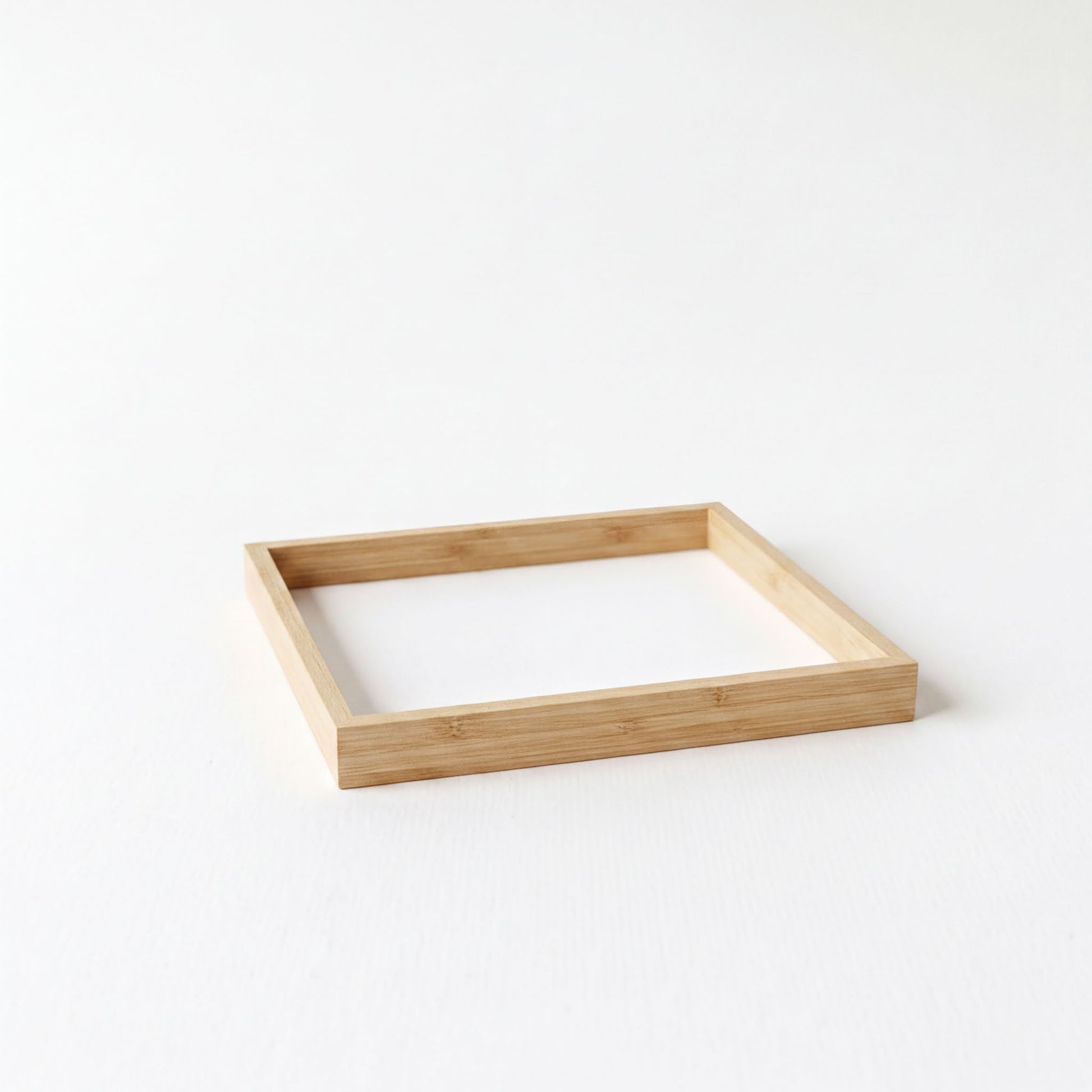 A simple, empty wooden frame sits on a plain white background.